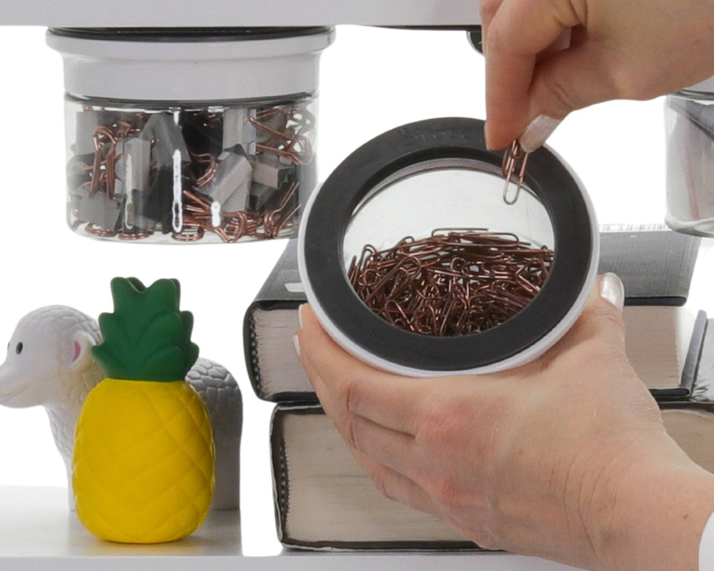 Hand accessing paper clips from a stash jar mounted under a shelf, showcasing fast access and efficient under cabinet storage solution.