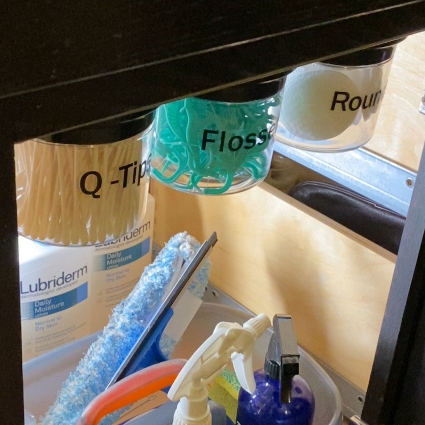 Under Sink/Under Shelf Organizer, Stainless POS jars labeled for Q-Tips, Flossers, and Rounds mounted under cabinet for efficient organization.