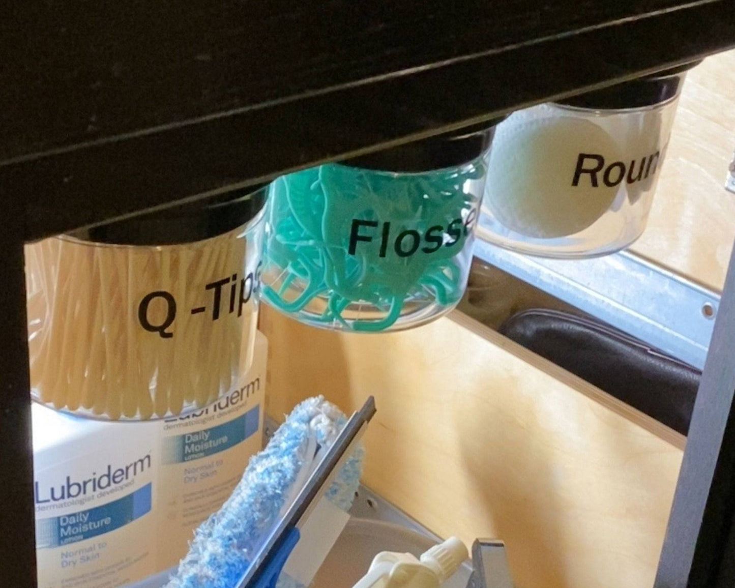 Under Sink/Under Shelf Organizer, Stainless POS jars labeled for Q-Tips, Flossers, and Rounds mounted under cabinet for efficient organization.