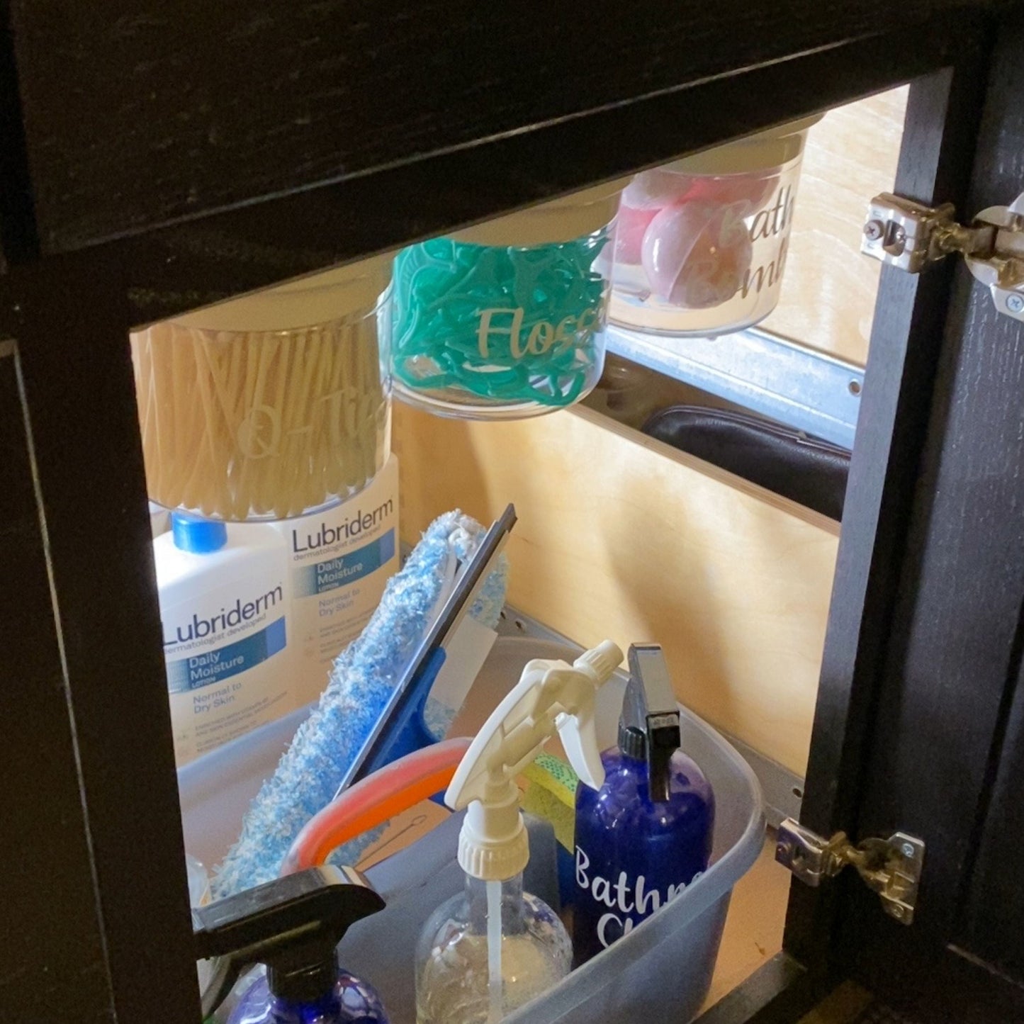 Under Sink/Under Shelf Organizer, Stainless POS jars labeled for flossers and Q-tips mounted under cabinet for efficient bathroom storage.