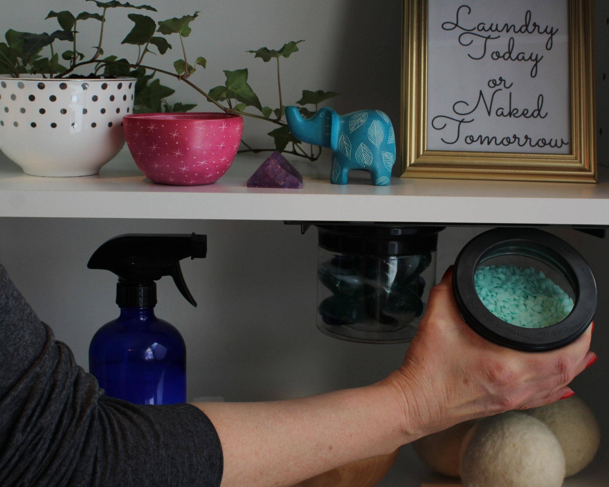 Hand accessing magnetic airtight jar with laundry detergent under shelf, highlighting sustainable and organized laundry storage.