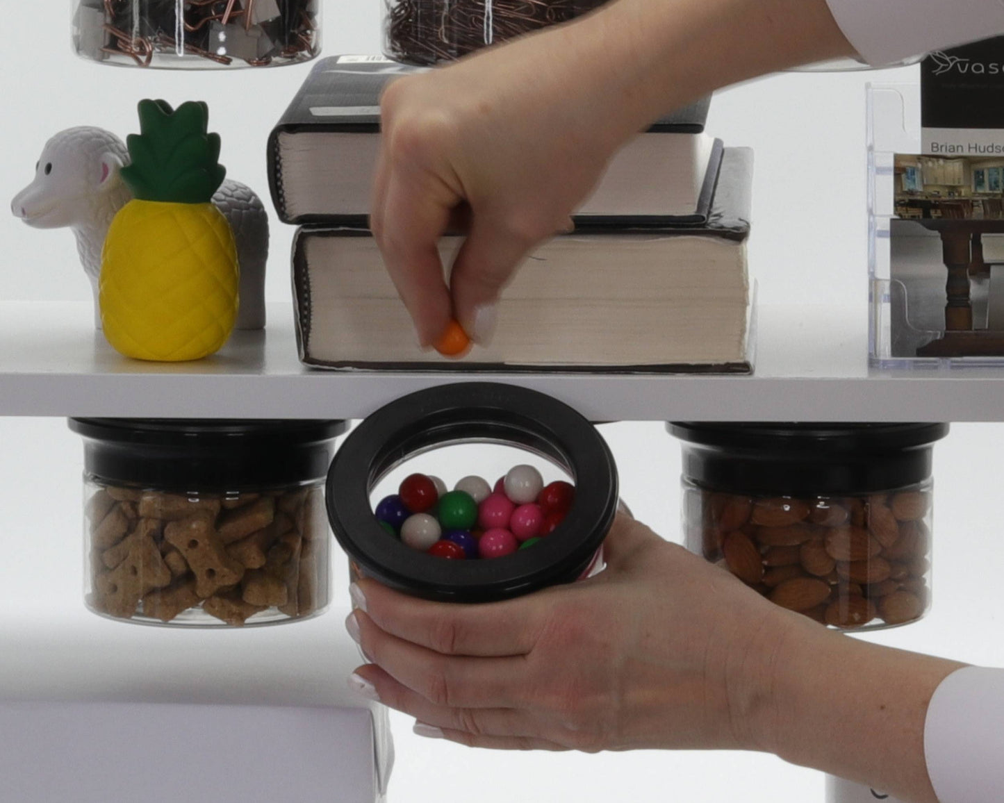 User grabbing candy from Office Stash Jar - Magnetic Jar under a shelf, showcasing colorful and accessible snack storage.