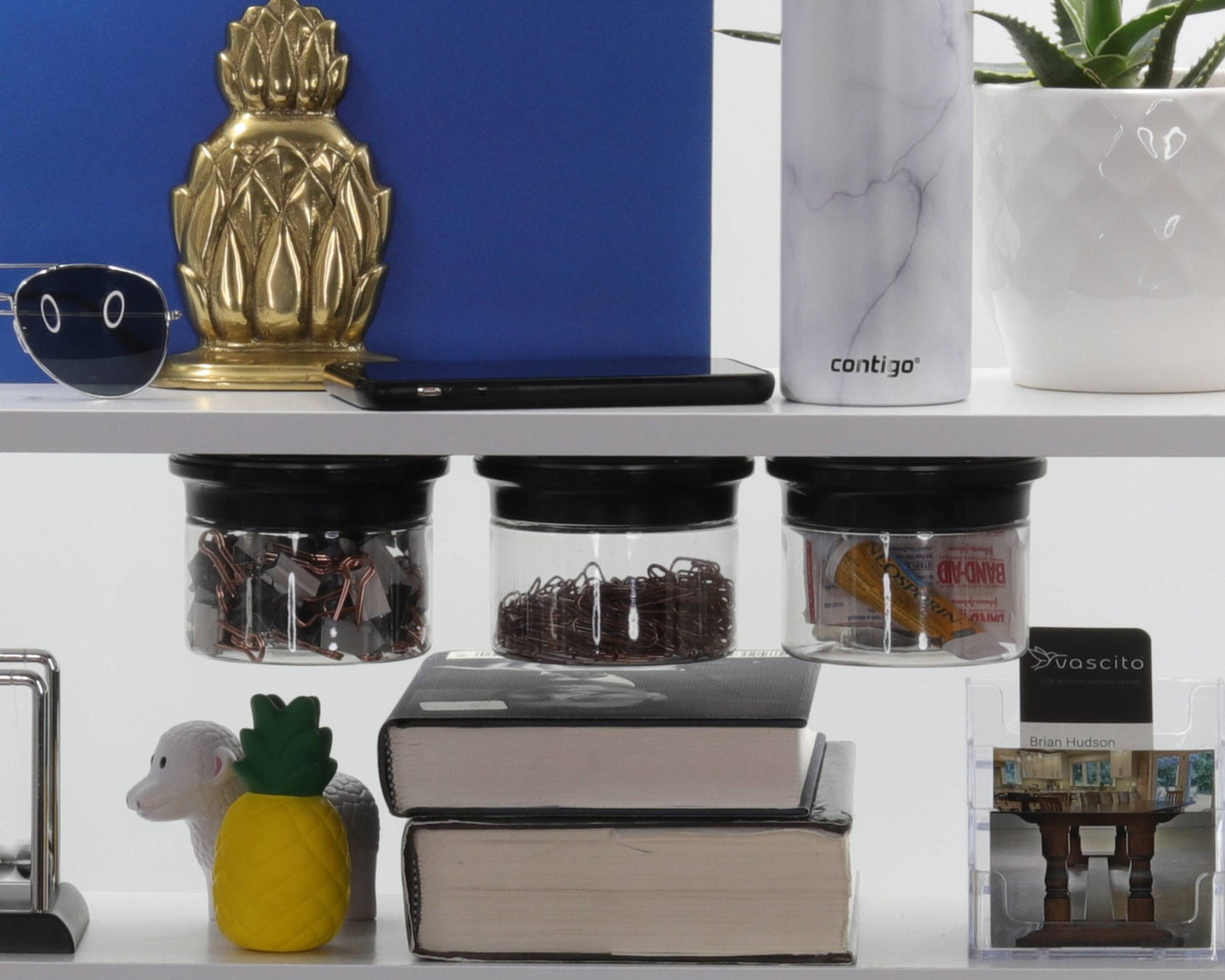 Office Stash Jars - Magnetic Jars mounted under a white office shelf storing paperclips and snacks, ideal for space-saving organization.