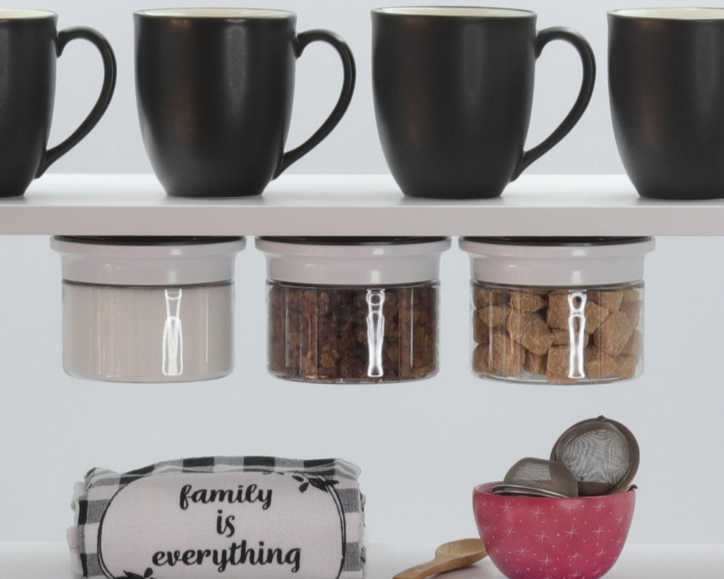Kitchen Organizer Stash Jars storing sugar and coffee above mugs and towels, maximizing under-shelf kitchen storage.