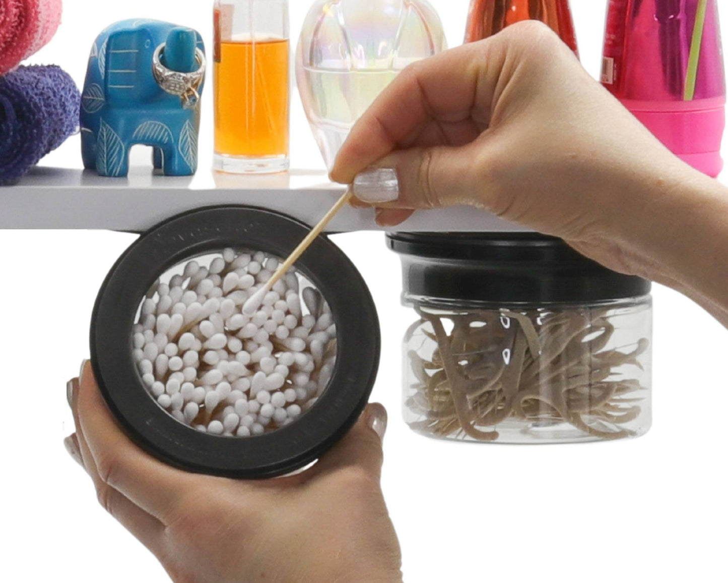 Hand accessing Q tip from under-shelf Cotton Ball Holder & Q Tip Organizer with black lid, ideal for bathroom storage and organization.