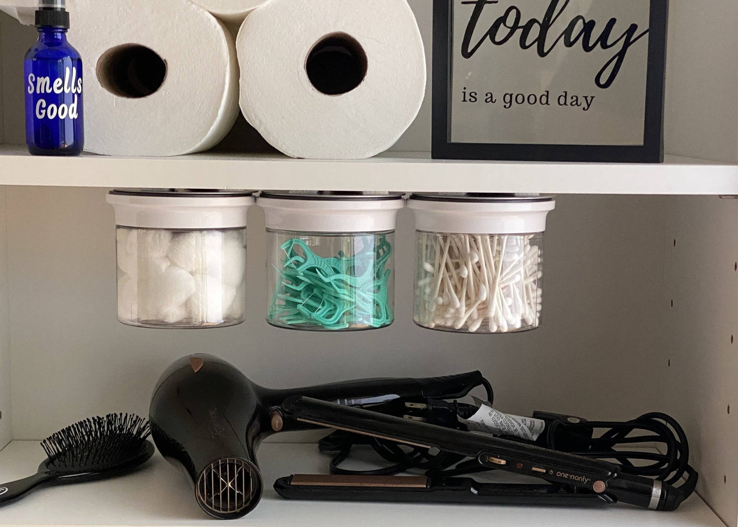 Bathroom Storage Organizer set with three under-shelf canisters holding cotton balls, Q tips, and hair ties, maximizing cabinet space.