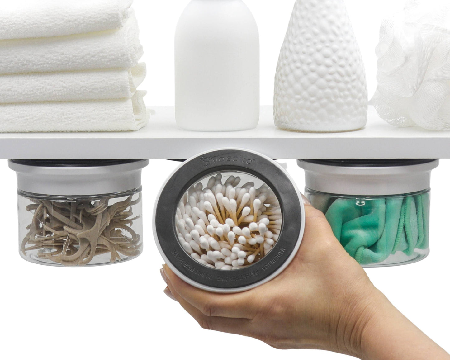 Cotton Ball Holder & Q Tip Organizer mounted under shelf with clear canisters storing cotton swabs, hair ties, and cloths in a bathroom setup.