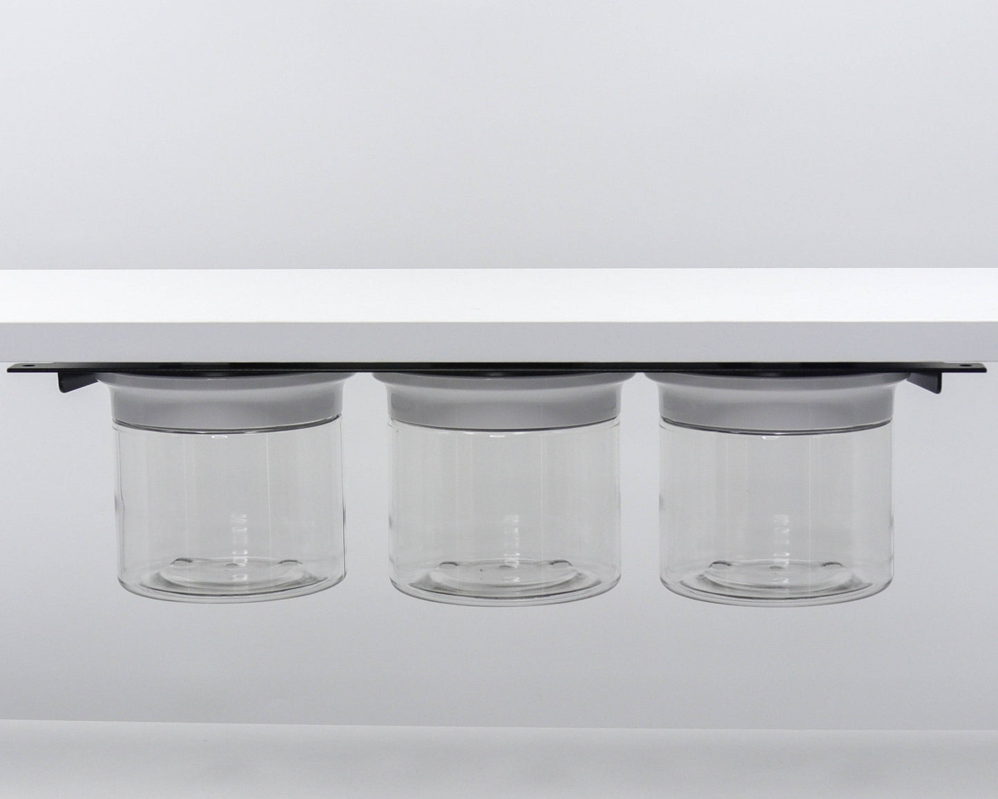 Triple canister set with white lids mounted under shelf. Perfect for organizing bathroom essentials in tight spaces.