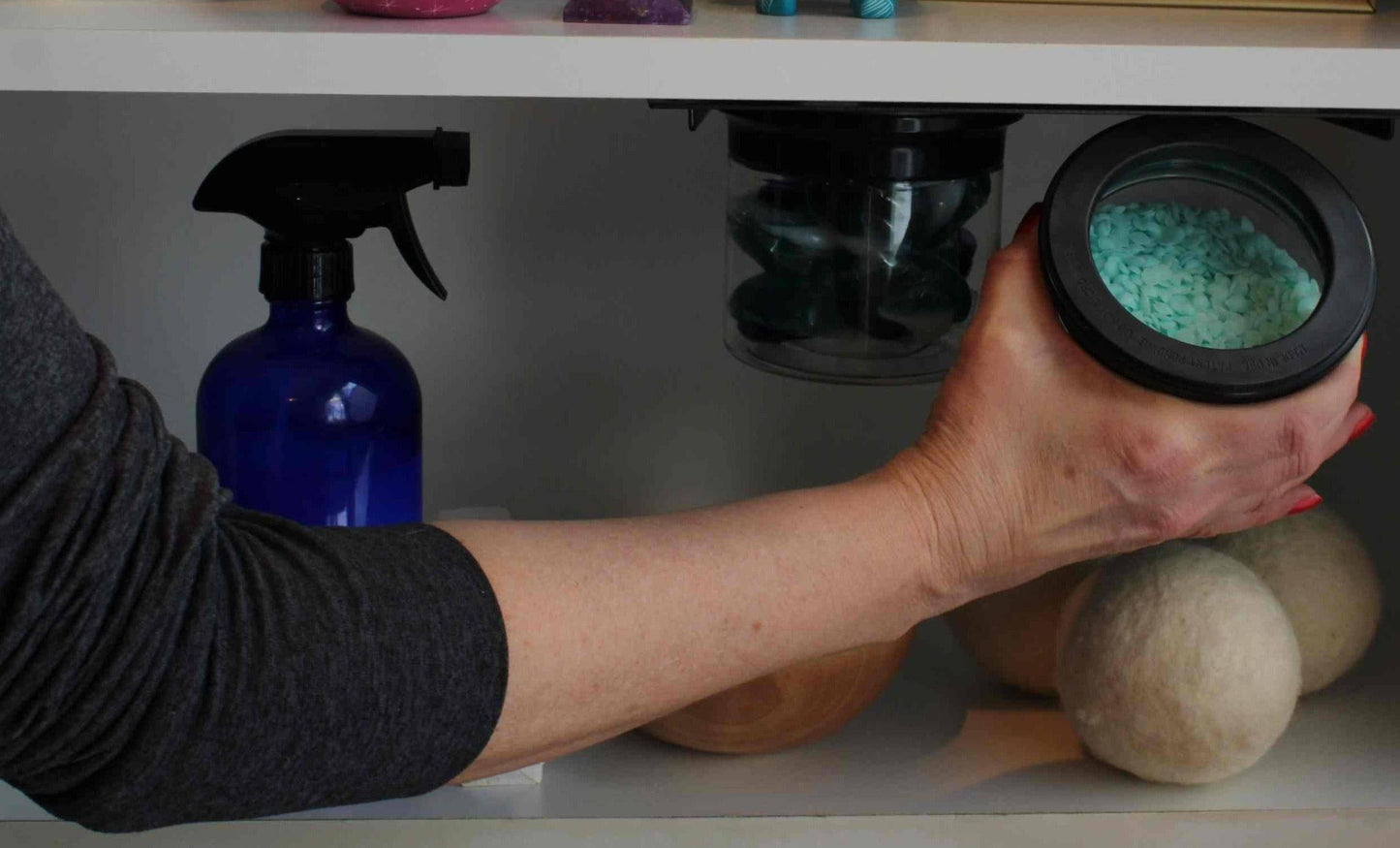 Person removing airtight jar filled with laundry scent beads from under sink organizer, part of Laundry Containers Organizer system for efficient storage.