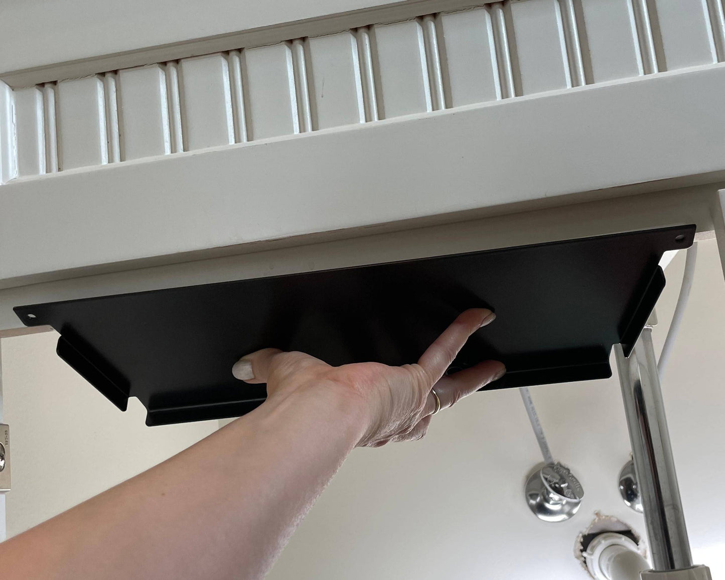 Hand installing under sink mounting plate for bathroom storage canisters. Easy-to-install solution for organizing toiletries.
