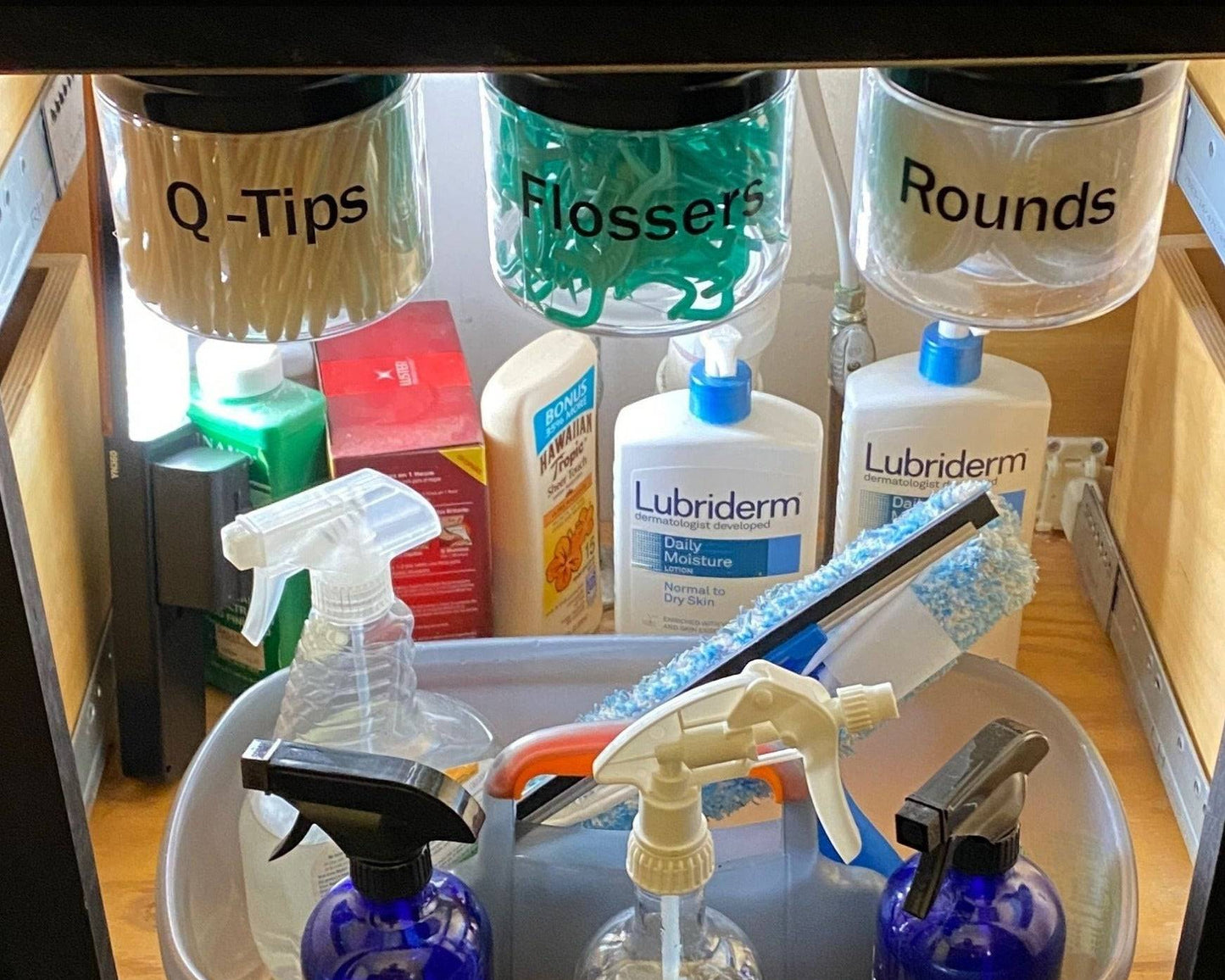 Under sink organizer with labeled canisters for Q-Tips, Flossers, and Rounds. Maximizes cabinet space for bathroom storage.