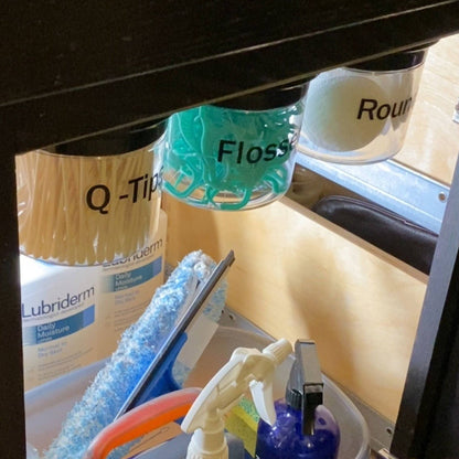 Under Sink/Under Shelf Organizer, Stainless POS jars labeled for Q-Tips, Flossers, and Rounds mounted under cabinet for efficient organization.