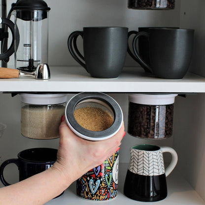 Hand removing brown sugar from magnetic airtight jar under shelf, showcasing efficient and accessible kitchen storage solution.