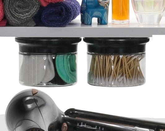 Under-shelf mounted canisters from Cotton Ball Holder & Q Tip Organizer set storing cotton pads and Q tips above hair tools.