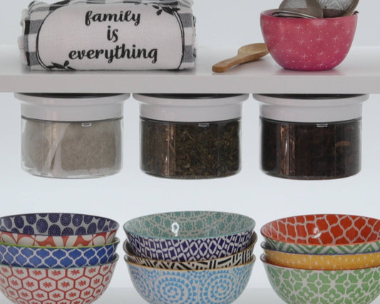 Colorful bowls and kitchen towels stored under shelf with Kitchen Organizer Stash Jars holding tea and spices above.