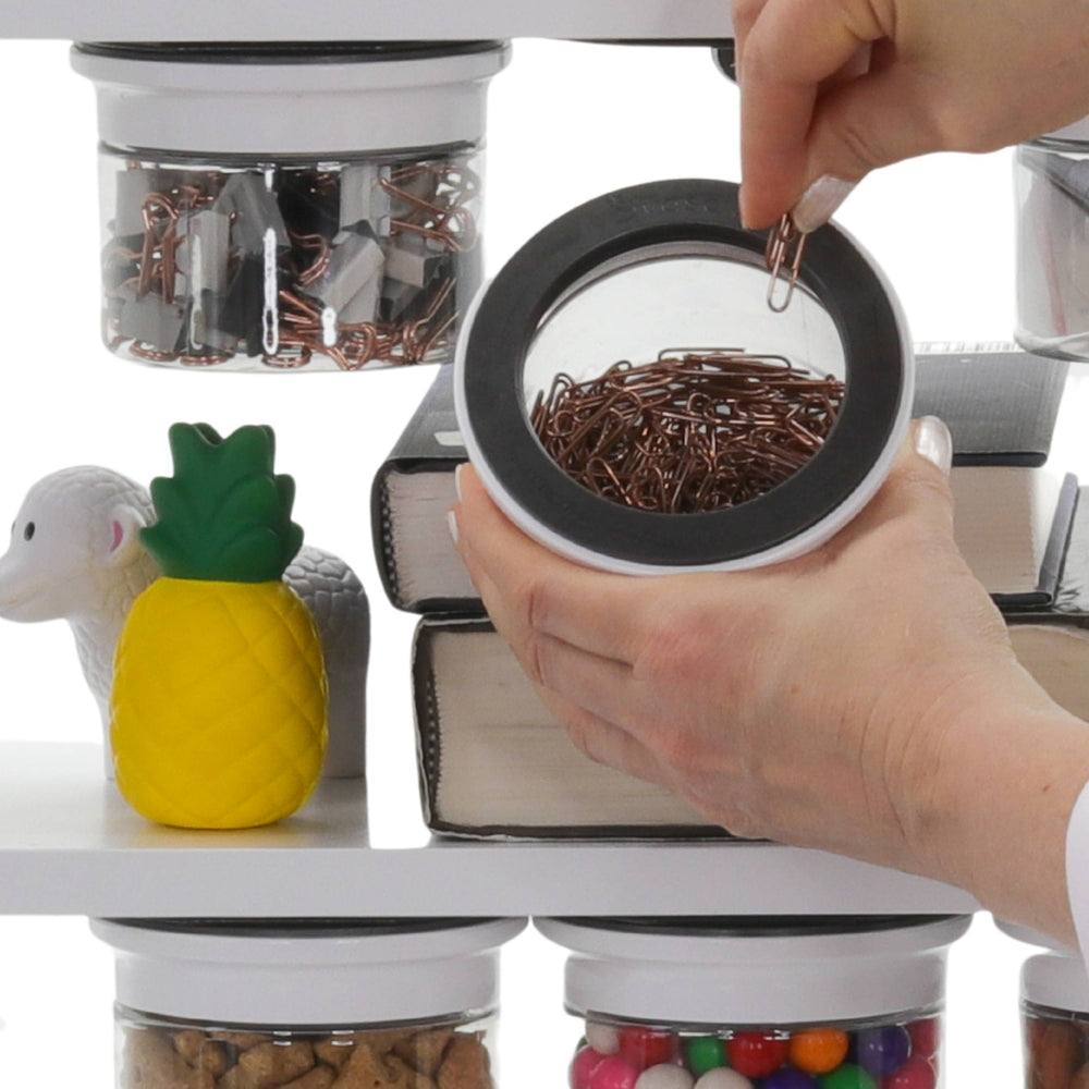 Hand accessing paperclips from an Office Stash Jar - Magnetic Jar mounted under a shelf, showcasing quick storage solution for office supplies.