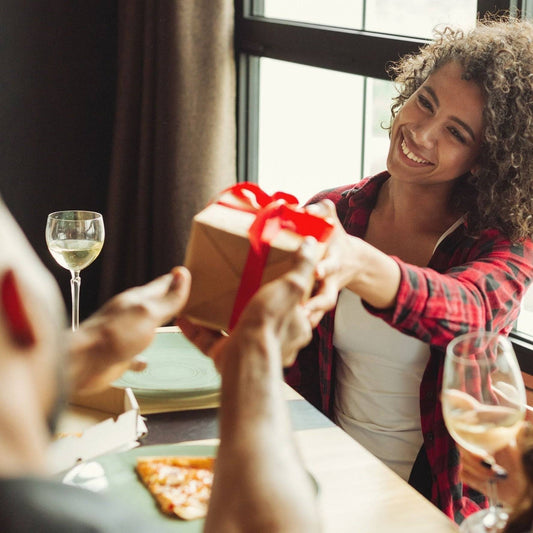 Smiling woman giving a wrapped Vascito Gift Card box across a dinner table, ideal for special occasions and instant gifting.