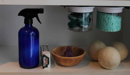 Under sink shelf with Laundry Containers Organizer jars storing detergent and scent beads, alongside laundry essentials like wool dryer balls and spray bottle.