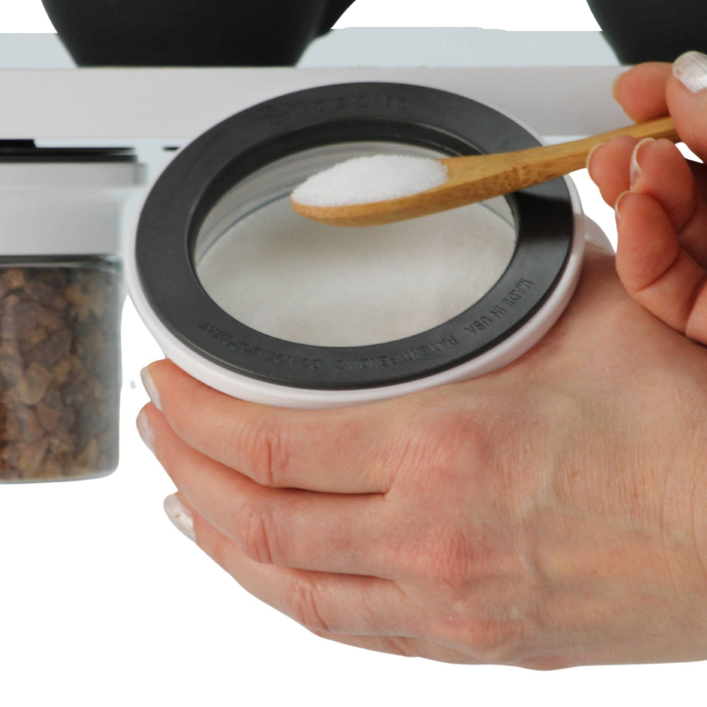 Hand scooping sugar from under-shelf Kitchen Organizer Stash Jar, showcasing easy access and airtight seal for kitchen use.