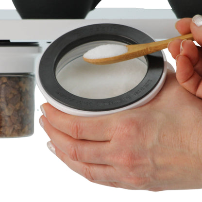 Hand scooping sugar from under-shelf Kitchen Organizer Stash Jar, showcasing easy access and airtight seal for kitchen use.